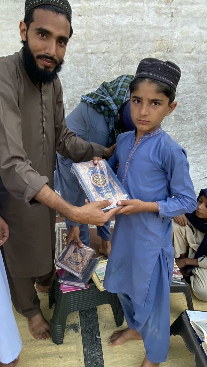 IRT Welfare Foundation volunteer giving a Quran Pak to a madrasah student