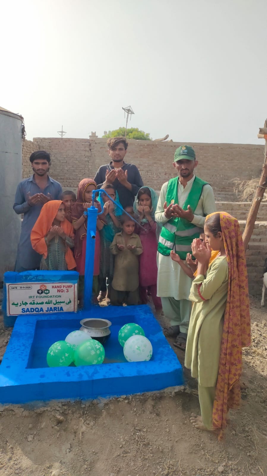 Family using a hand pump water well donated as sadaqah jariyah for parents in Pakistan